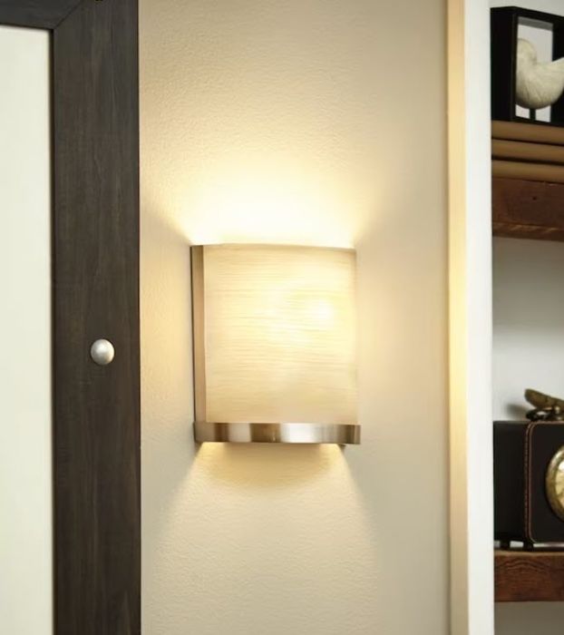 A sleek, wall-mounted light fixture brightens a beige-toned room adorned with wooden shelves and accents.