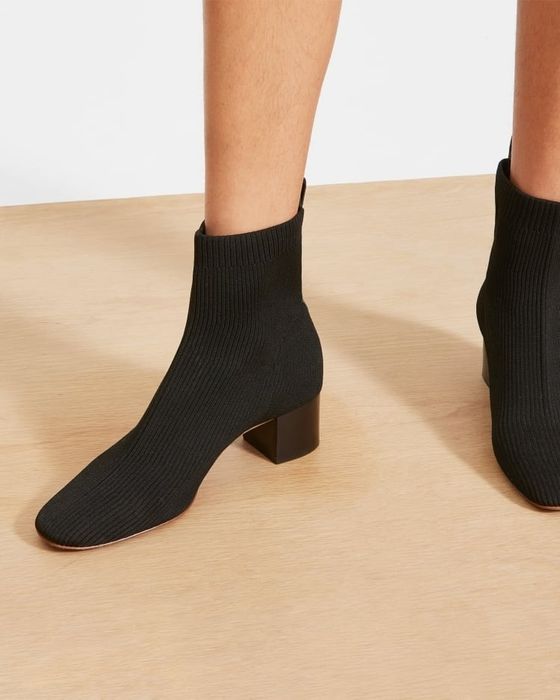 A close-up shot of a person's feet in black ankle-high sock boots with block heels, ideal for a shopping guide on footwear.