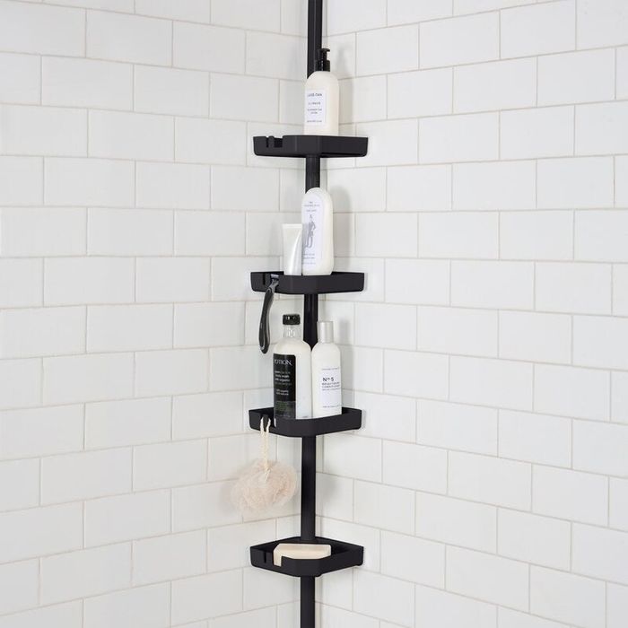 A sleek black tension pole shower caddy standing in a shower, neatly storing various bath products.
