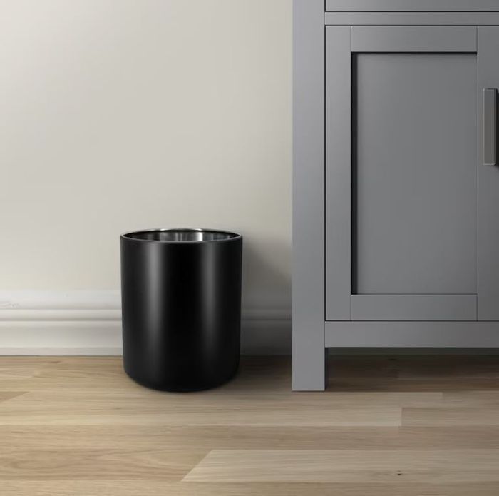 A stylish black waste bin sits beside a contemporary gray cabinet on a hardwood floor, creating a modern aesthetic.