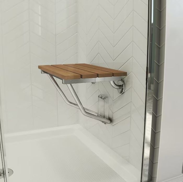 A tiled shower area equipped with a foldable wooden bench mounted on the wall, offering both functionality and accessibility.