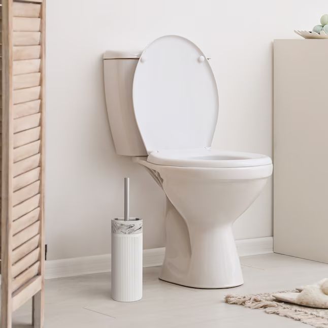 A contemporary bathroom setup featuring a toilet and a marble-patterned toilet brush holder, showcasing minimalist design for modern homes.