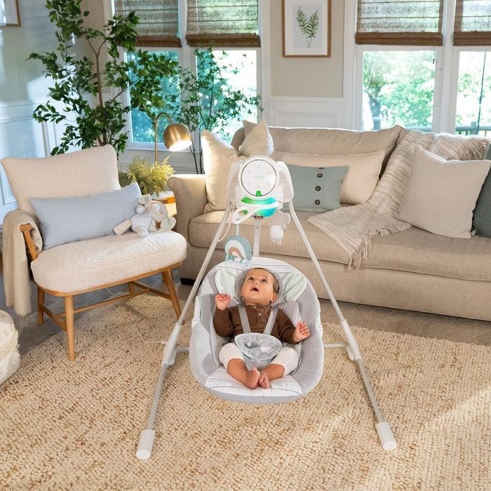 A baby enjoying a motorized swing in a stylish living room adorned with modern furniture and decorative plants.