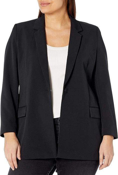 Individual sporting a one-button blazer layered over a white top and dark trousers. The person's face is obscured. No other people are visible in the image