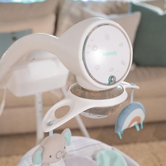 A baby swing equipped with plush toys, gentle sounds, and adjustable noise, vibration, and light settings, perfect for newborn comfort and nursery aesthetics.