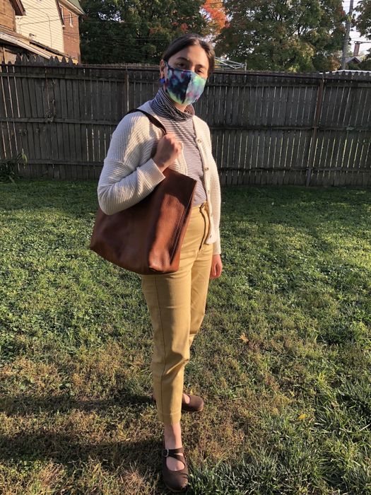The writer holding the medium brown leather tote casually over her shoulder.