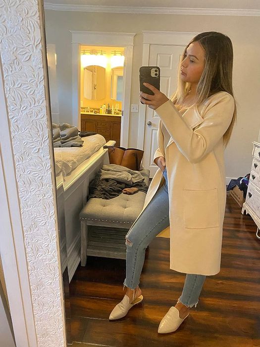 A reviewer styled in a beige cardigan paired with denim jeans
