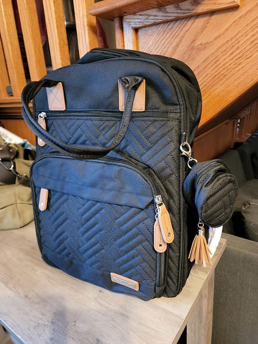 A chic black quilted backpack featuring stylish tan accents.