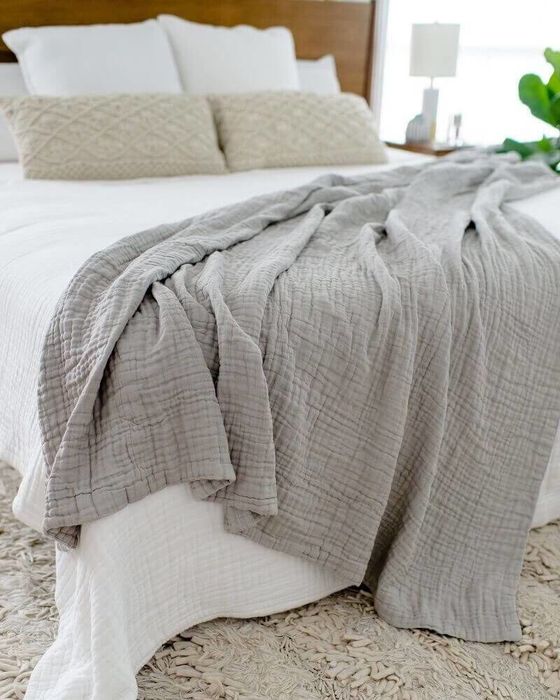 A gray waffle muslin blanket elegantly draped at the end of a bed.