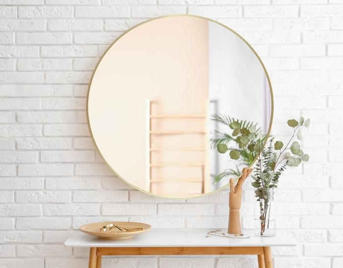 A round wall mirror with a sophisticated gold trim.