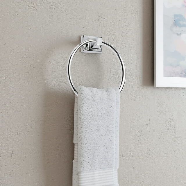 A silver towel ring with a white towel hanging from it.