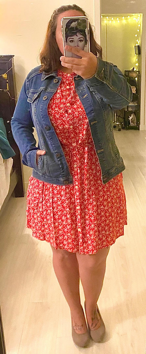 The reviewer is styled in a blue jean jacket paired with a vibrant red dress.