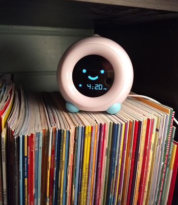 A reviewer's clock placed on a bookshelf