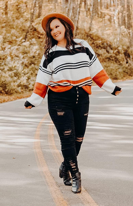 A reviewer showcasing the sweater with white, black, and orange stripes