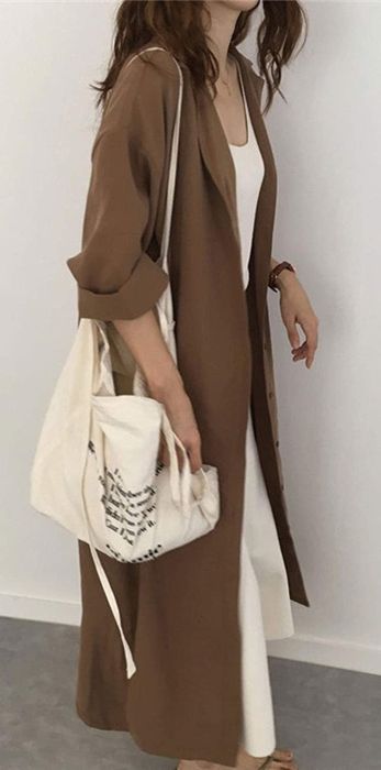 A model wearing a brown maxi dress styled open like a jacket, adding an effortless layer to the look.