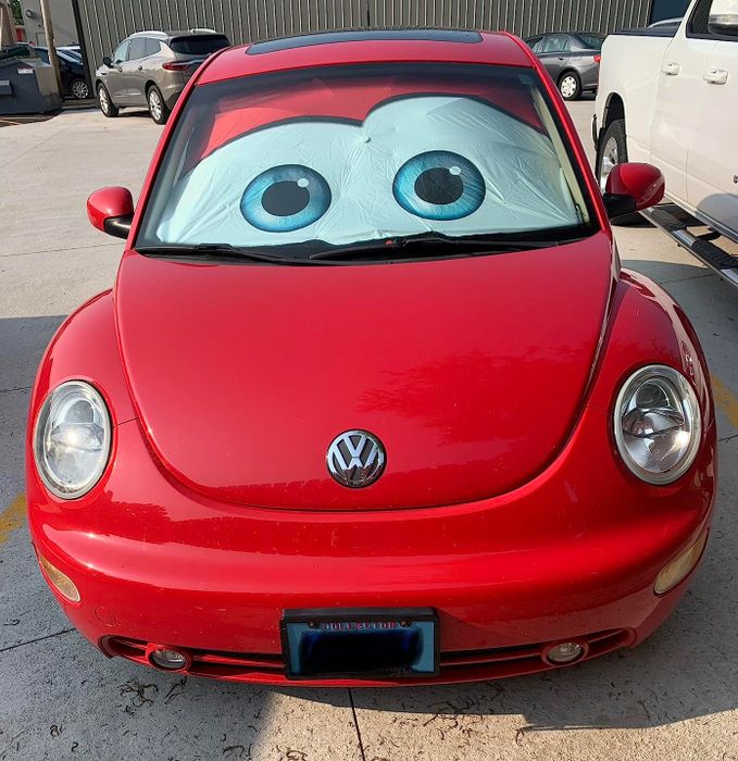 A red Volkswagen Beetle with oversized cartoon eyes attached to its windshield.