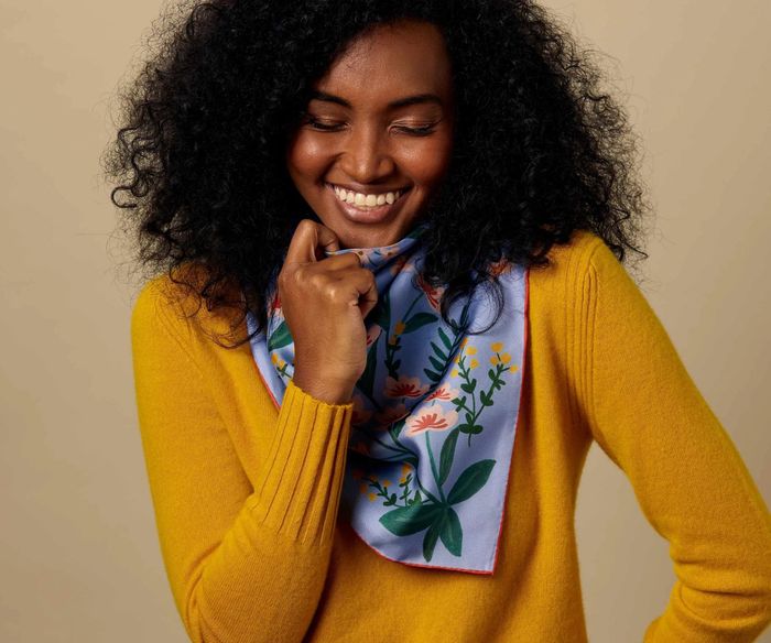 A model gracefully drapes the scarf around their neck, showing off its luxurious feel.
