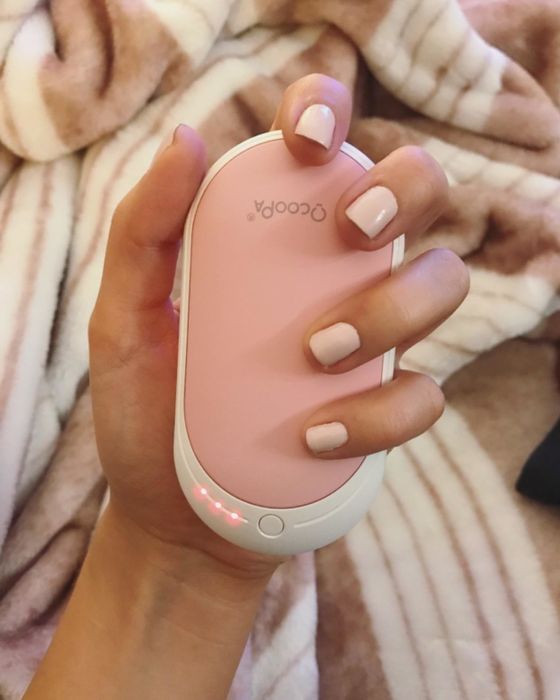 A hand holding the rechargeable hand warmer.
