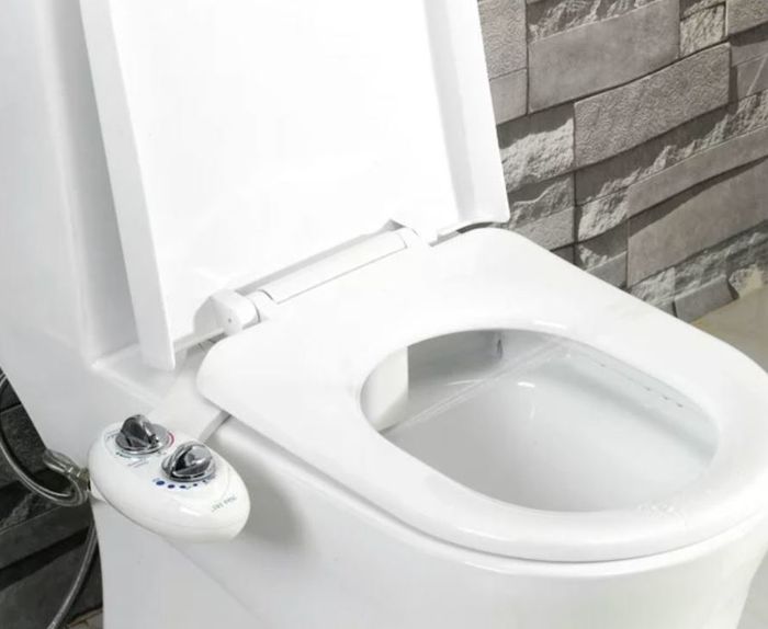 A bidet attachment installed on a white toilet.