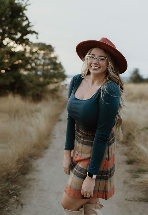 A reviewer is wearing the green long-sleeve bodysuit paired with a skirt.