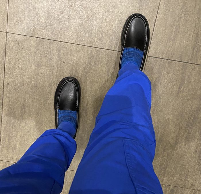 Reviewer sporting black loafers with blue socks and scrubs