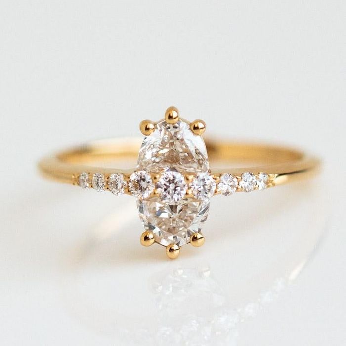 the ring featuring a gold band, two half-moon diamonds creating an oval shape, and smaller diamonds positioned in the center