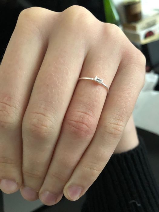 a reviewer showcasing the delicate ring, featuring a petite stone and slender band