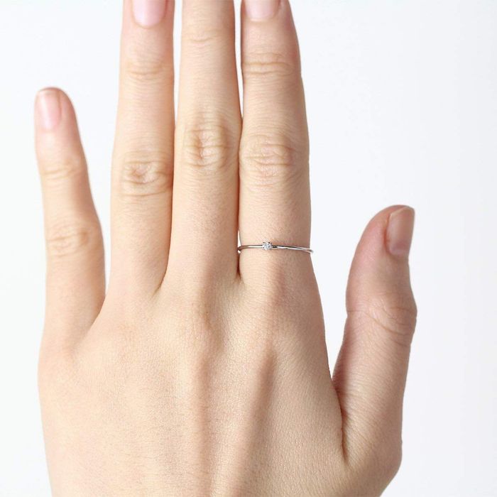 A model wearing a slim band ring featuring a small stone delicately positioned in the center