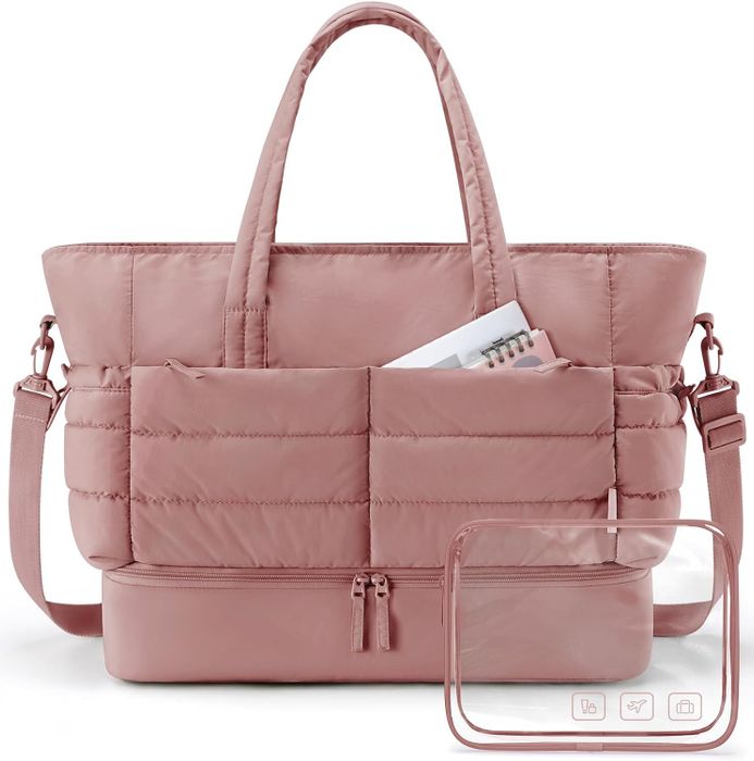 A large tote bag with several pockets, holding a book, planner, and a small clear makeup pouch adorned with travel icons.