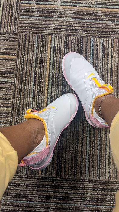 Reviewer wearing white sneakers with pink and yellow accents