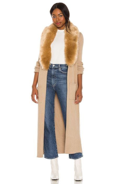 A model dons a long beige fur sweater.