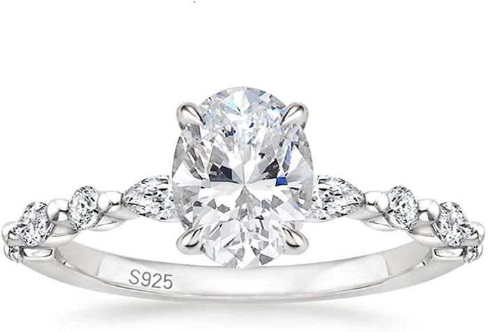 The ring features an oval center stone surrounded by smaller diamonds on a twisted band