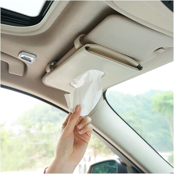 A hand grabs a tissue from a car's sun visor tissue holder, showcasing a practical accessory for easy access while driving.