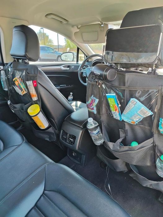 Backseat organizers for car seats are stocked with items like wipes, snacks, water bottles, and electronics, offering practical organizational solutions for family road trips.