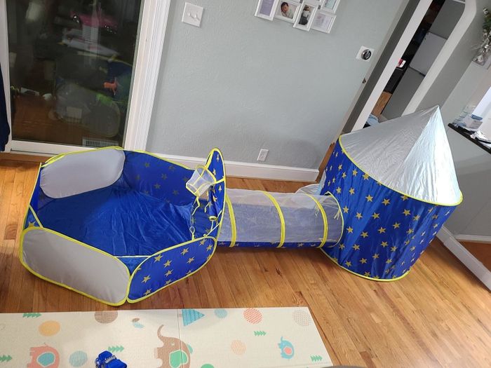 a photo from a reviewer displaying the tent, tunnel, and ball pit set up in a family living space