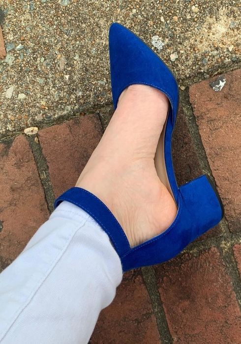 A reviewer wearing the same style of pump in dark blue paired with skinny gray pants.