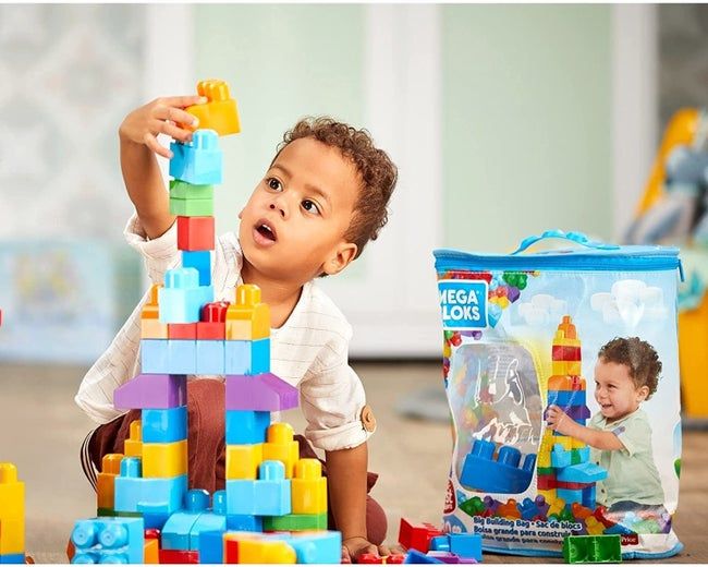 a child playing with oversized building blocks, with a storage bag visible nearby