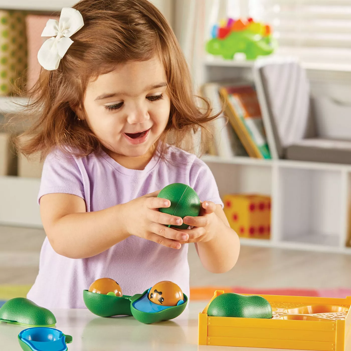 A young child playing with a green plastic avocado toy