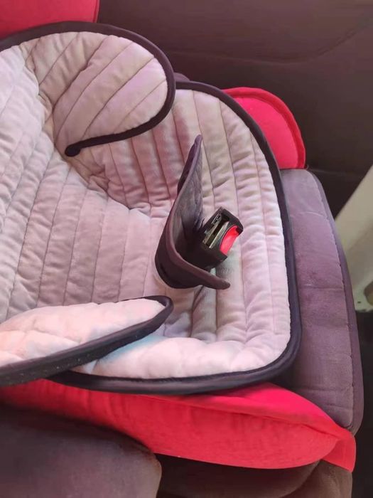 A baby car seat with padded lining and red accents, shown from a side angle in a shopping setting.
