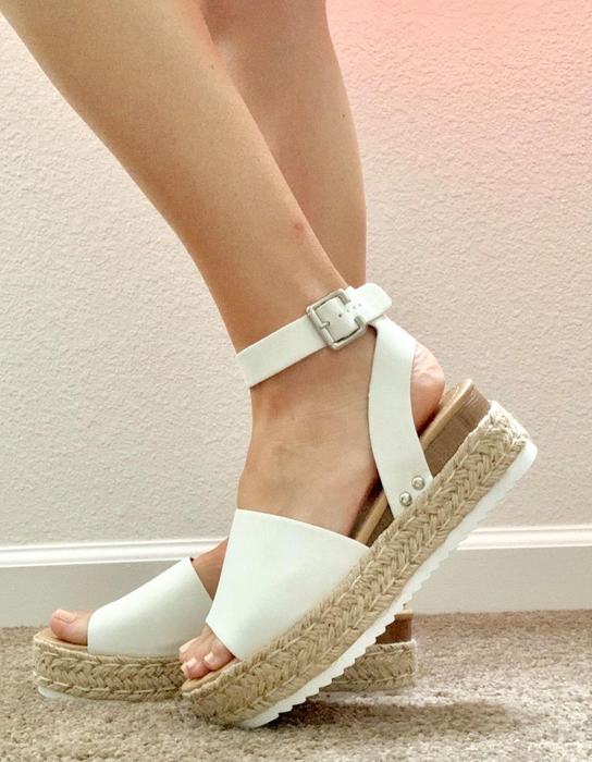 A close-up shot of the reviewer in the white sandals.