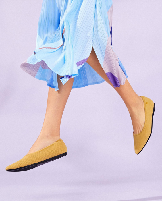A model wearing pointed-toe knit flats in yellow.