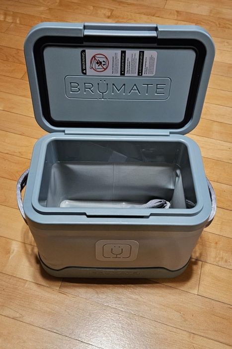 An open BrüMate cooler displayed on a wooden floor, showcasing its spacious interior, perfect for keeping items cool while traveling or during outdoor activities.