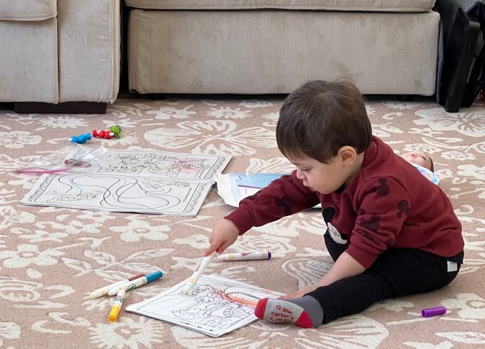 A child deeply engrossed in coloring, surrounded by vibrant drawings and crayons scattered on the floor