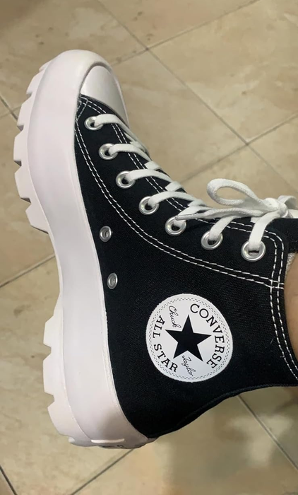 Reviewer sporting classic high-top Converse sneakers with a chunky sole.