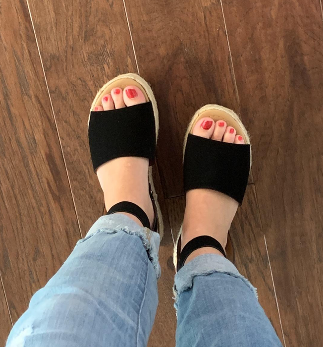 Person wearing stylish black sandals.