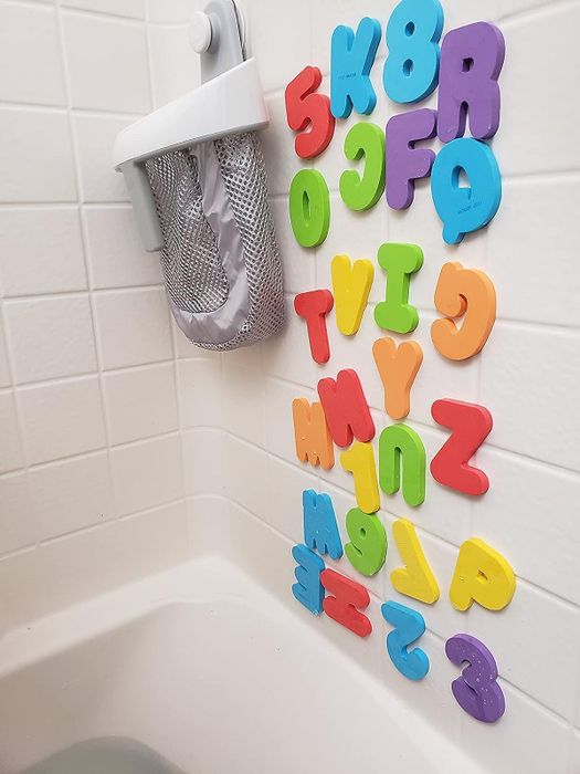 Foam letters and numbers arranged along the edge of a bathtub.