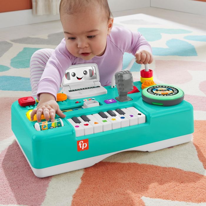 a baby enjoying playtime with the DJ turntable set, which is set up without its legs
