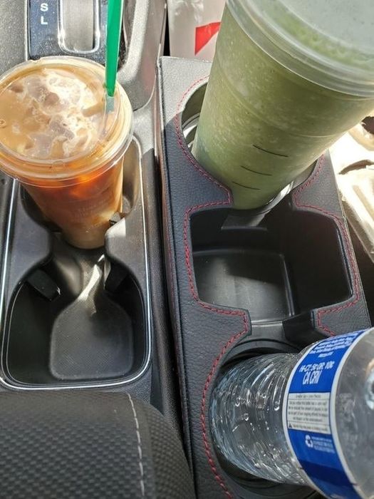 Another reviewer's photo of the console organizer holding a Starbucks cup and a water bottle.