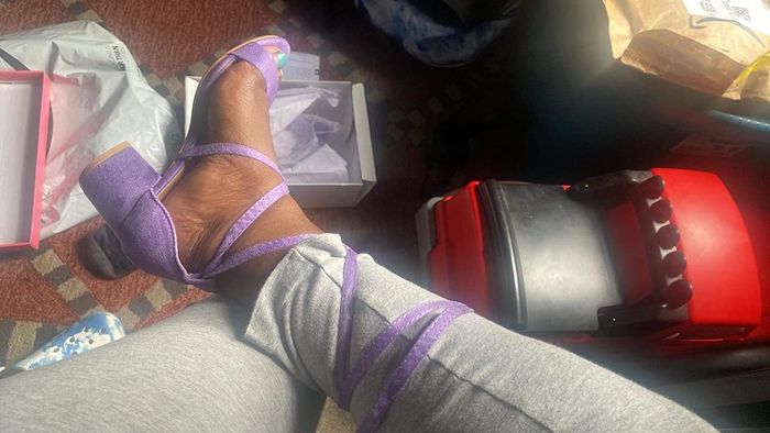 Person showcasing purple strap sandals surrounded by packaging materials, suggesting a recent unboxing or purchase
