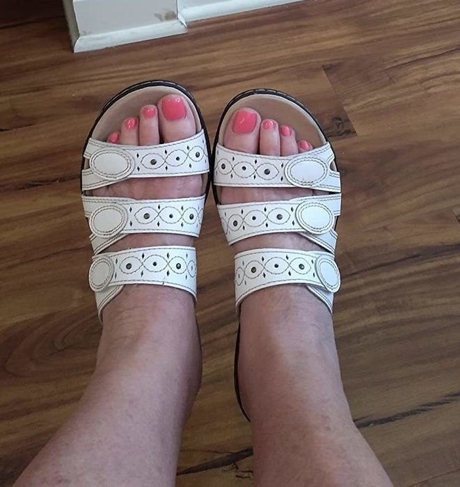 A reviewer showcasing white sandals